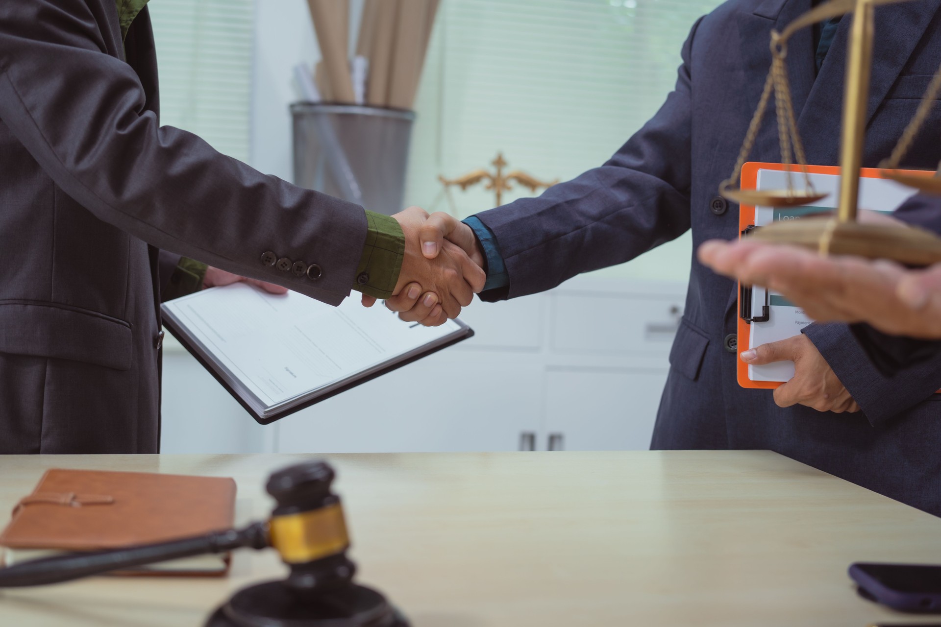 Three lawyers in a meeting at the table in an office, shaking hands discussing business, focusing on civil,commercial,labor, marketing,advertising laws to ensure legal compliance prevent lawsuits