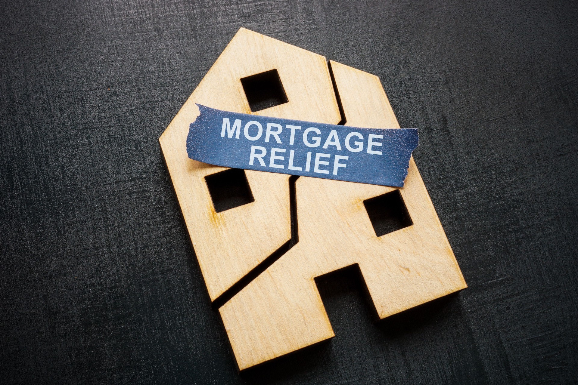Mortgage relief. Broken house model and fastening tape.