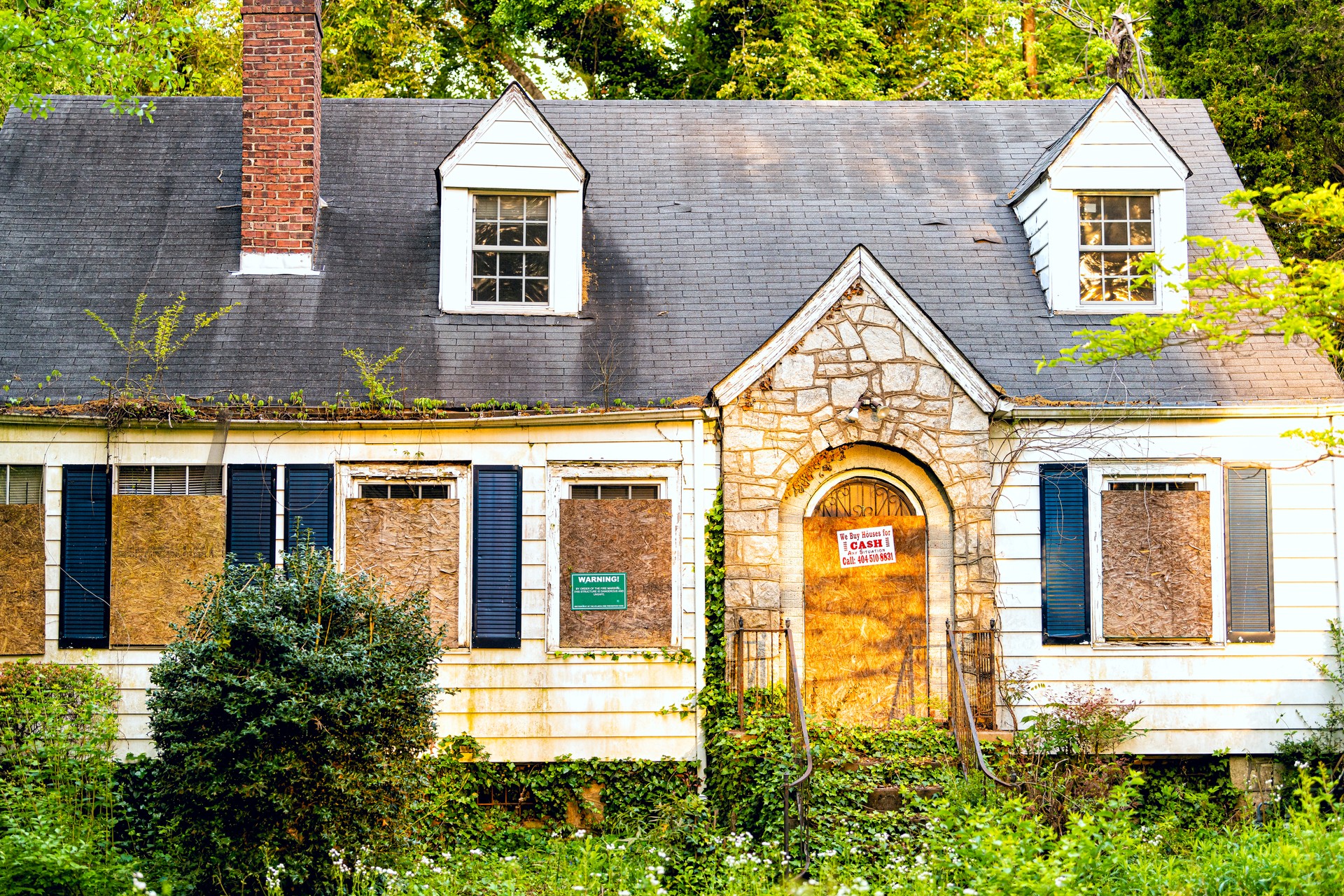 Old abandoned wooden house entrance and warning sign, company buying for cash in Atlanta, Georgia